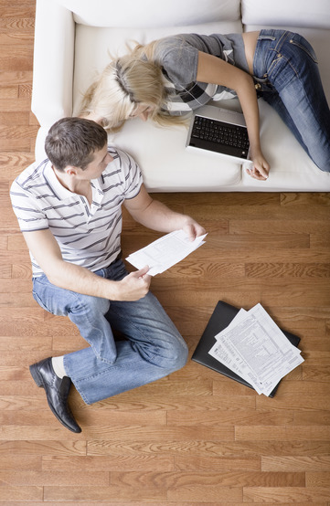 High angle view of a young couple working on a laptop and paperwork. Vertical shot.