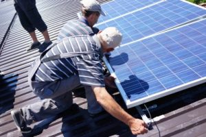 Man installing alternative energy photovoltaic solar panels on r