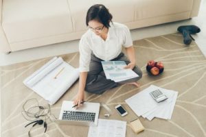 Young business woman working with papers while sitting on the floor at home