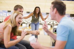 Four young adults laughing and gesturing in a bowling alley