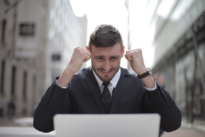 man on computer with hands up